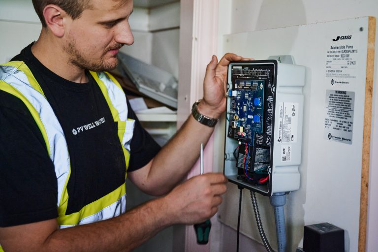 Plumber changing settings on a Franklin Electric constant pressure well pump controller.